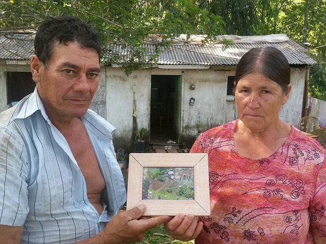 Agricultores Nelson e Eva exibem fotografia do terreno onde viveram por 23 anos. Ao fundo, o casebre para onde se mudaram na sexta-feira / Daniel Giovanaz